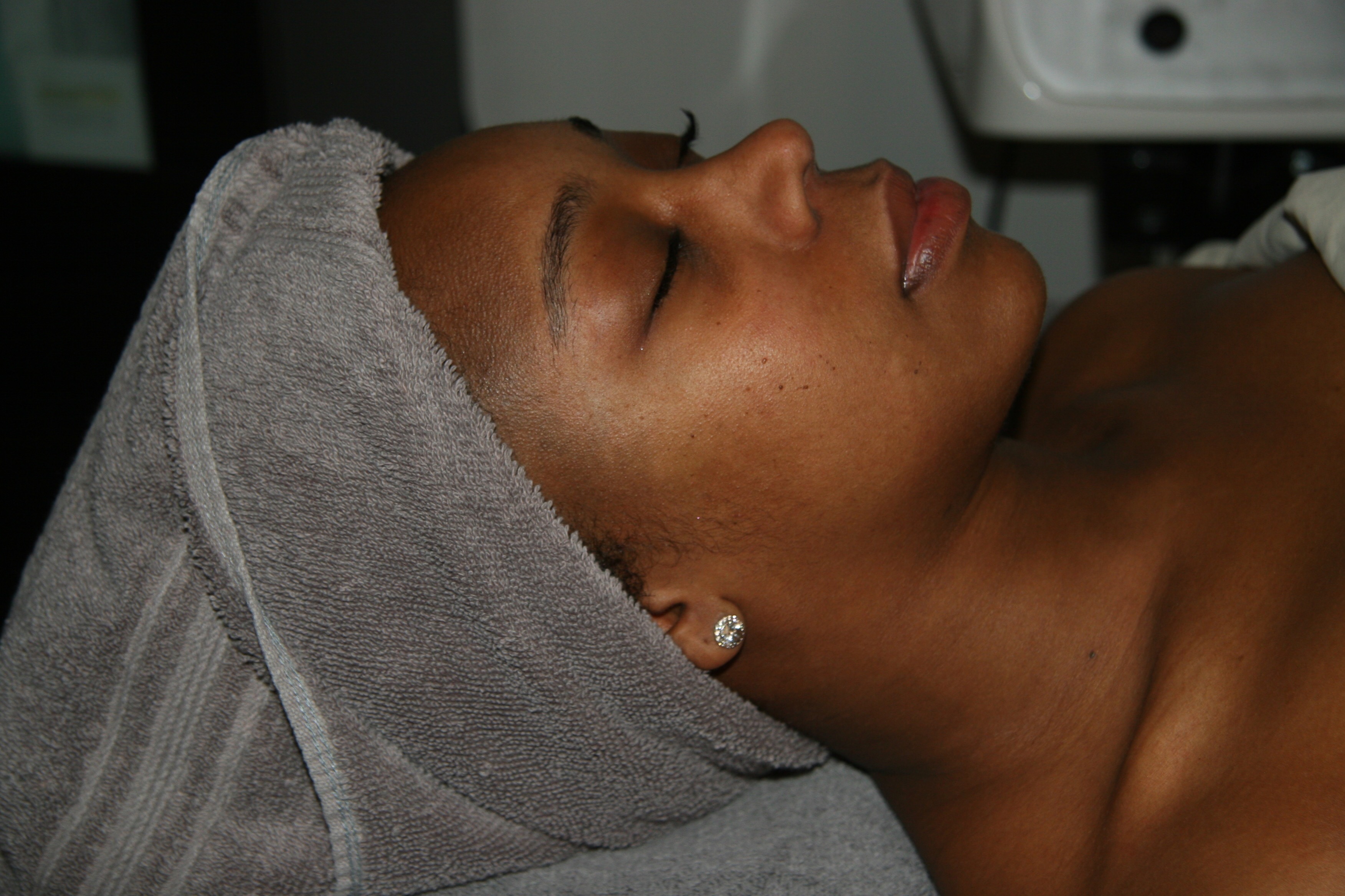 An African-American woman with a towel on her head in an esthetist's office