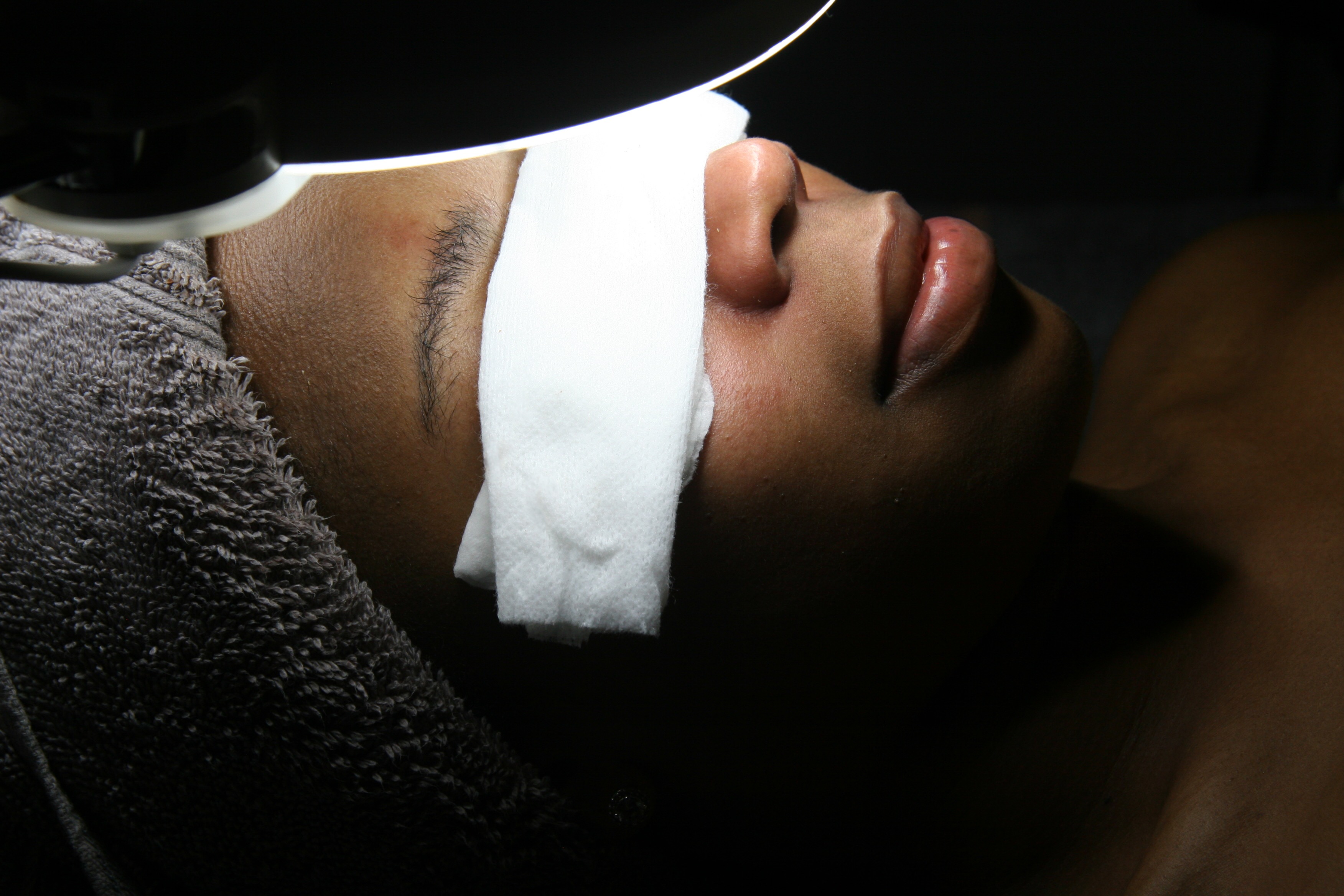 An African-American woman under a bright light with a cloth over her eyes