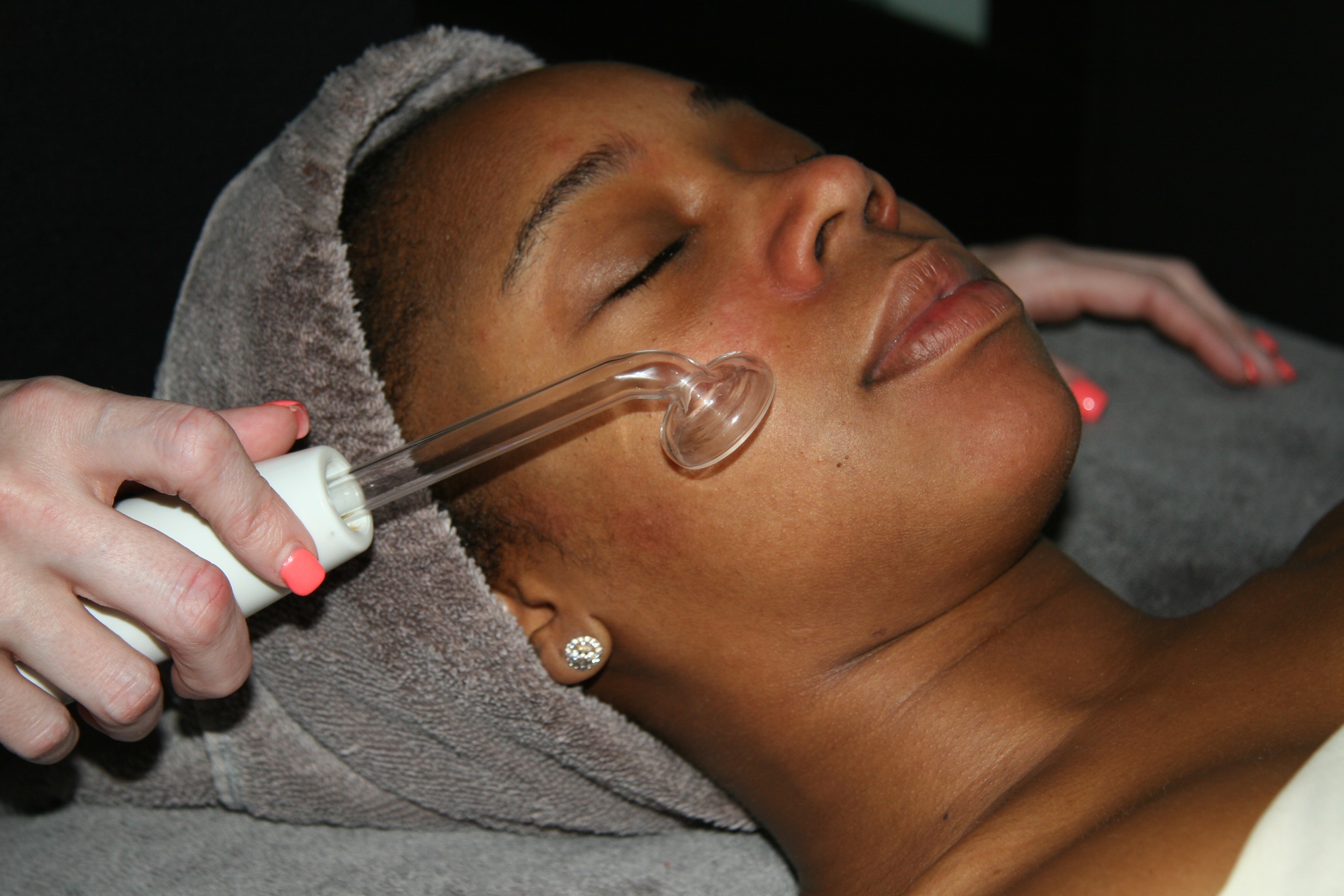 An African-American woman receiving a treatment on her face with a plastic suction device